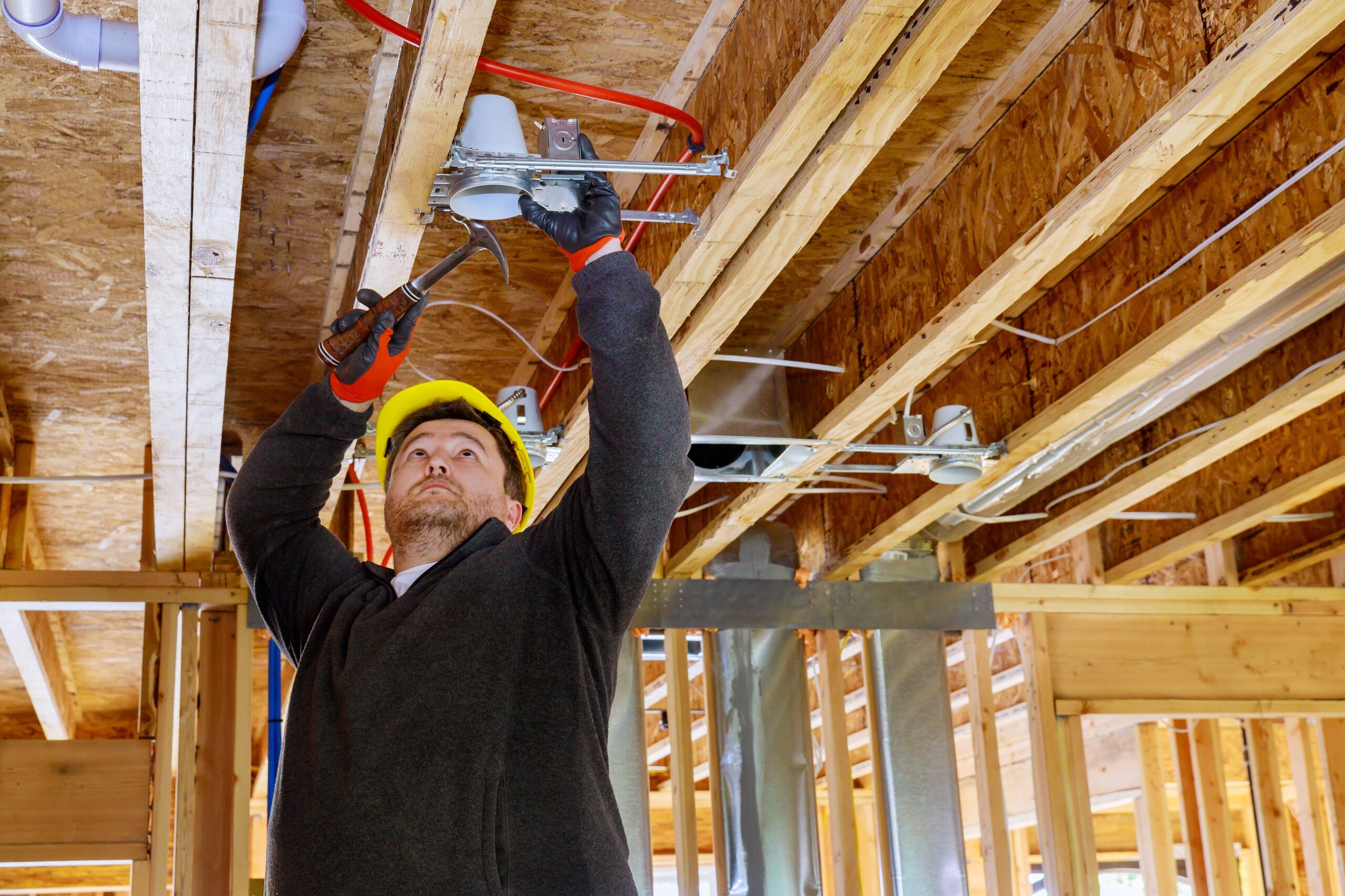 The electrician nailing to the ceiling lamp, installs the lighting lamp in the laying ceiling